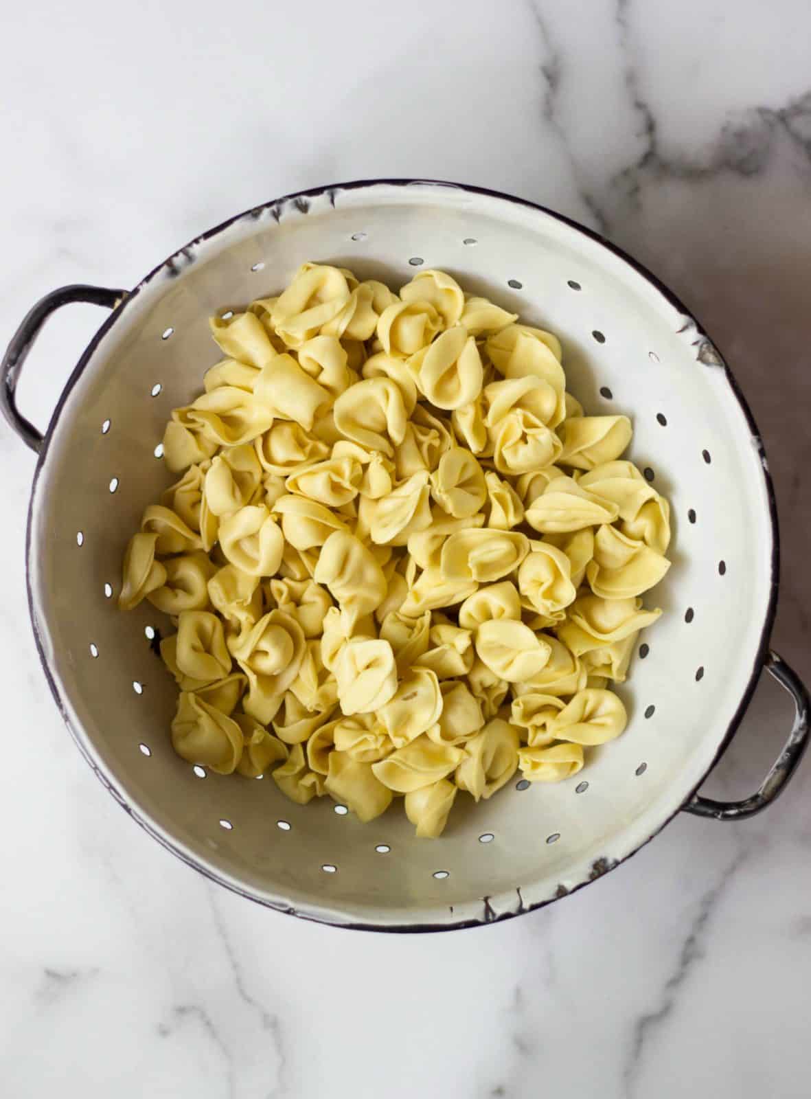 Tortellini in a white colander.