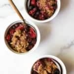 Mixed berry crisp in white dishes with spoons