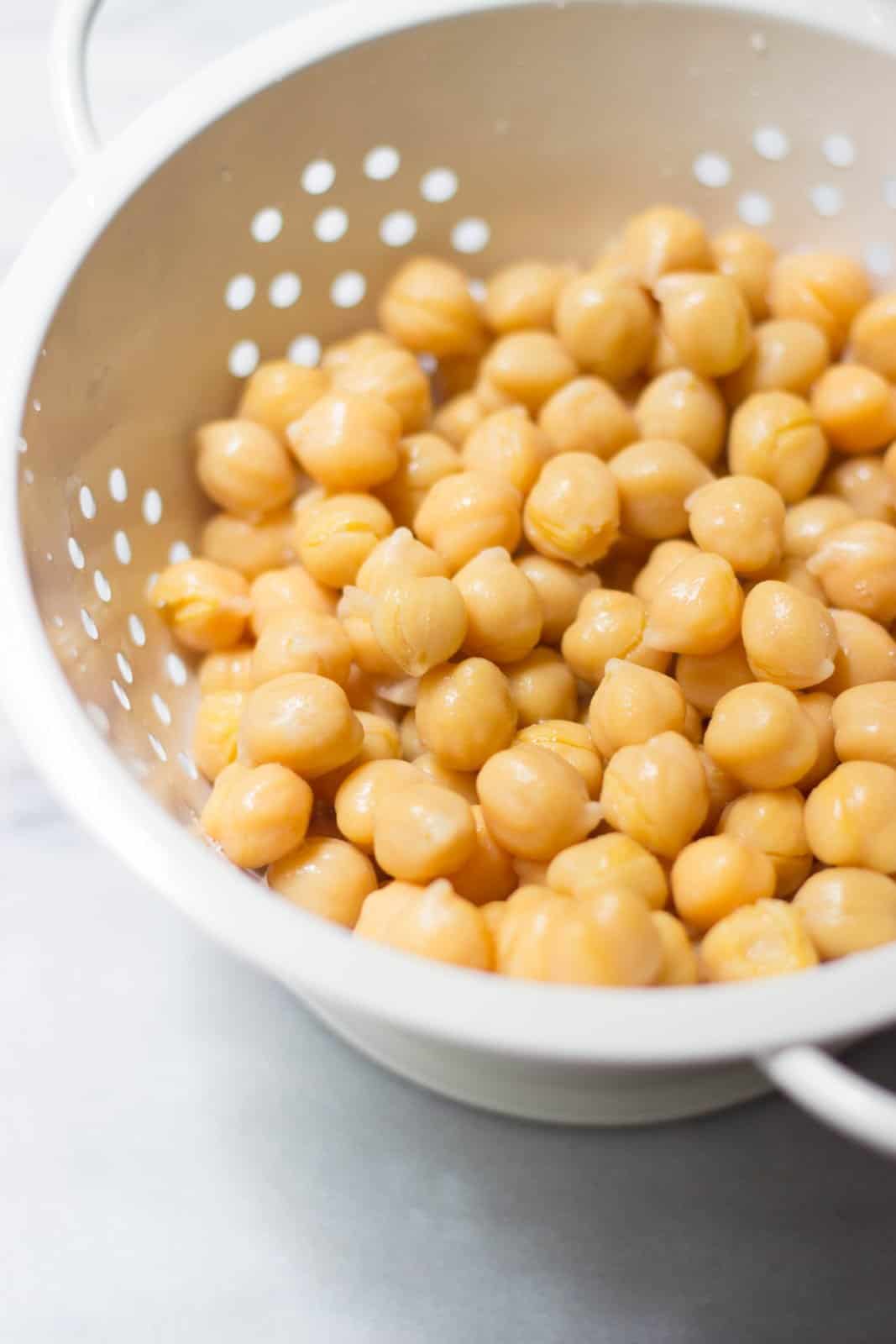 Chickpeas in a white colander as an example of things you can buy bulk to save money on groceries.