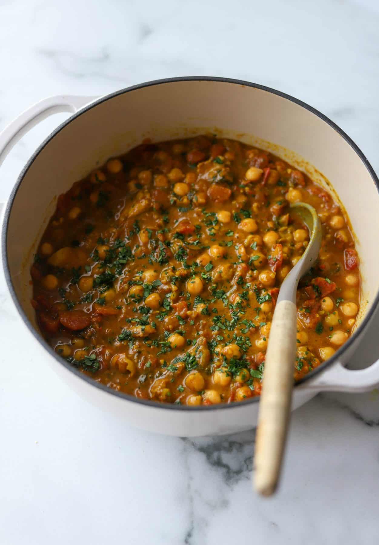 A white pot filled with chickpea coconut curry.