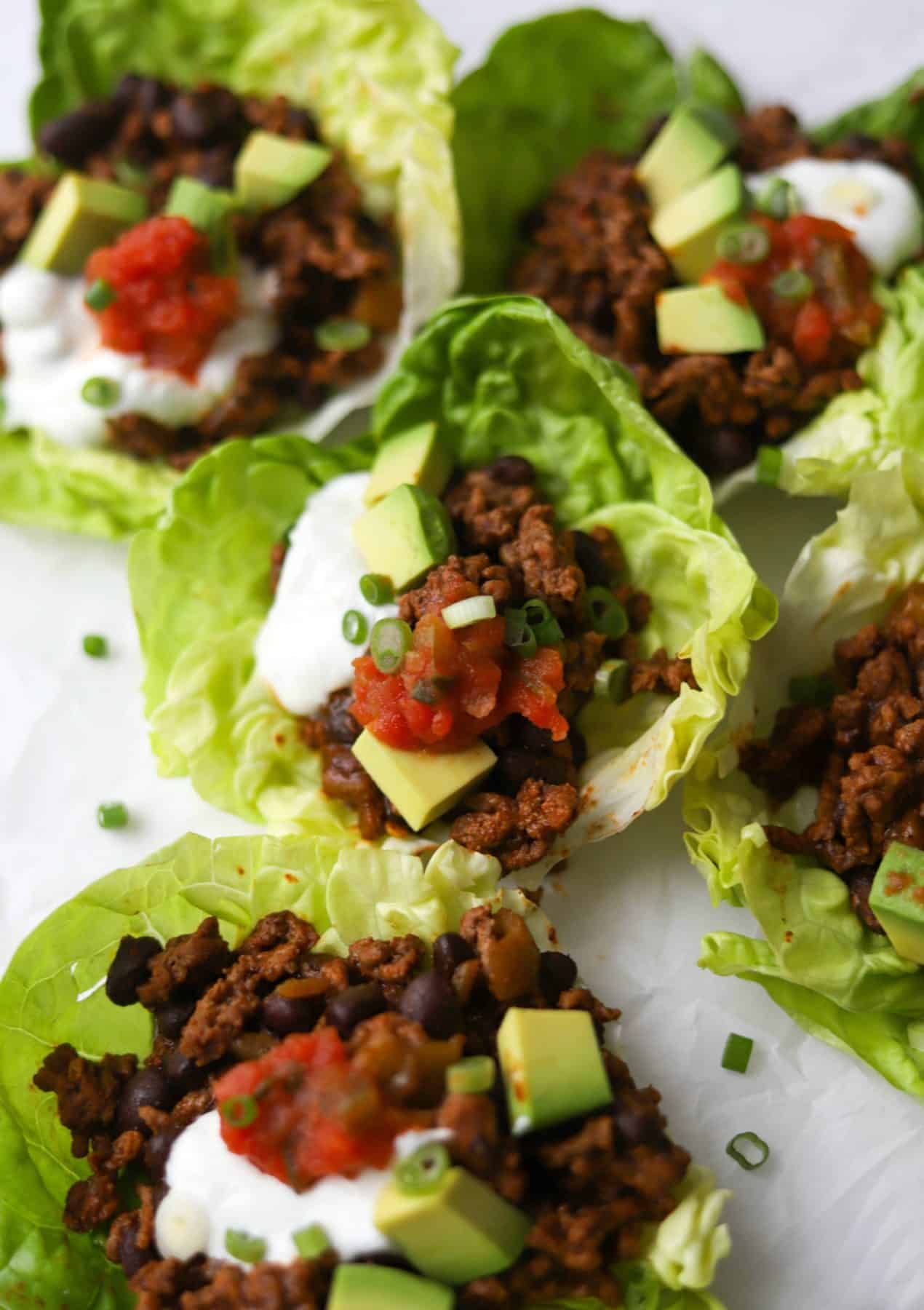 Taco lettuce cups on a plate made with black beans. 