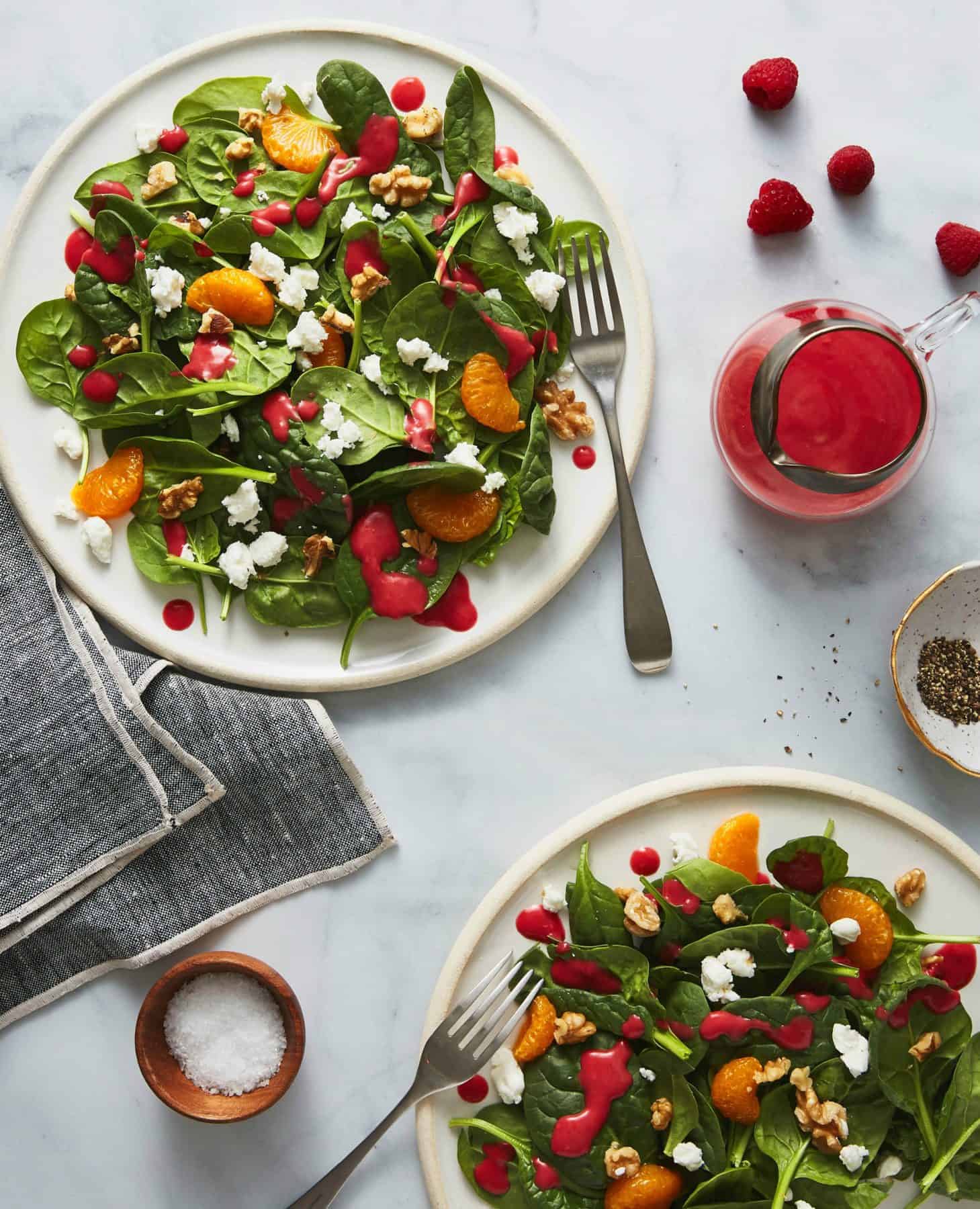 Spinach, Goat Cheese & Walnut Salad with Raspberry Vinaigrette on white plates