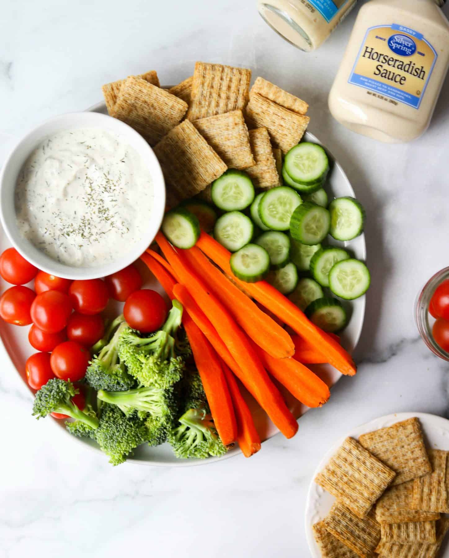 Plate full of veggies and crackers with horseradish dip