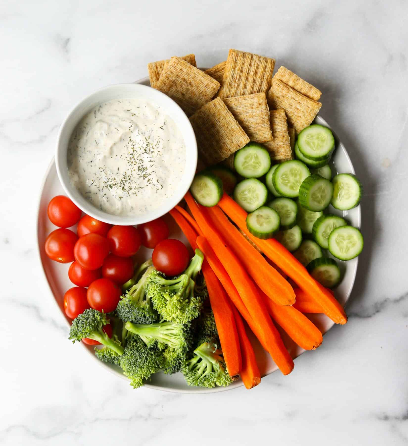 Veggie tray on white marble backdrop.