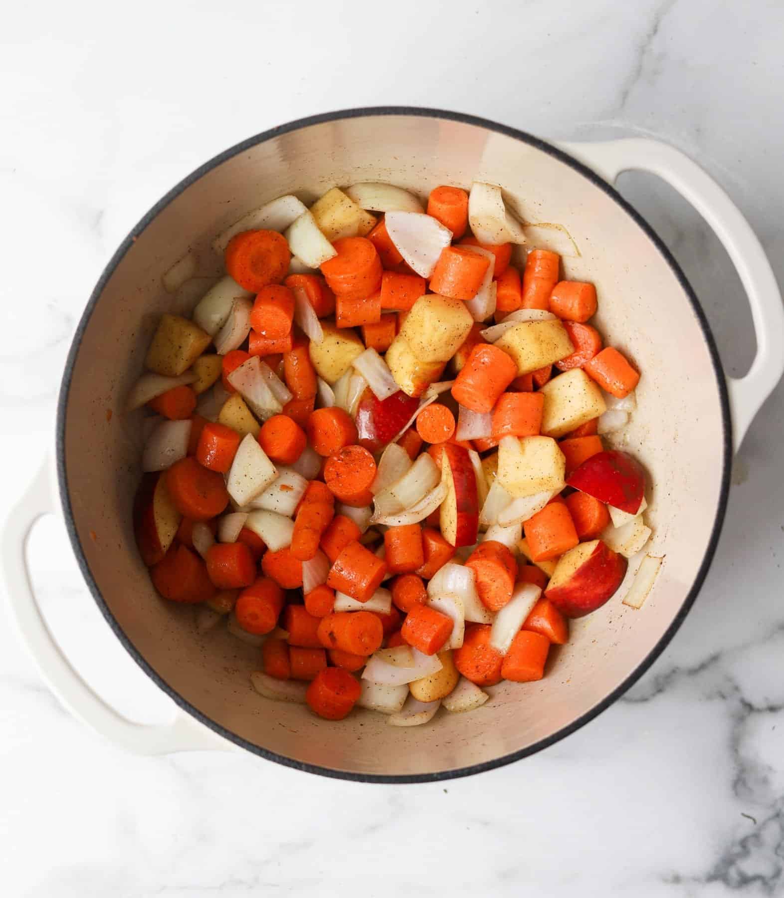 Carrot ginger soup ingredients in a white pot