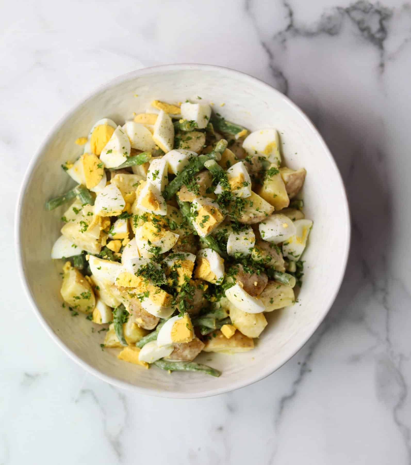 Green bean potato salad in a white bowl