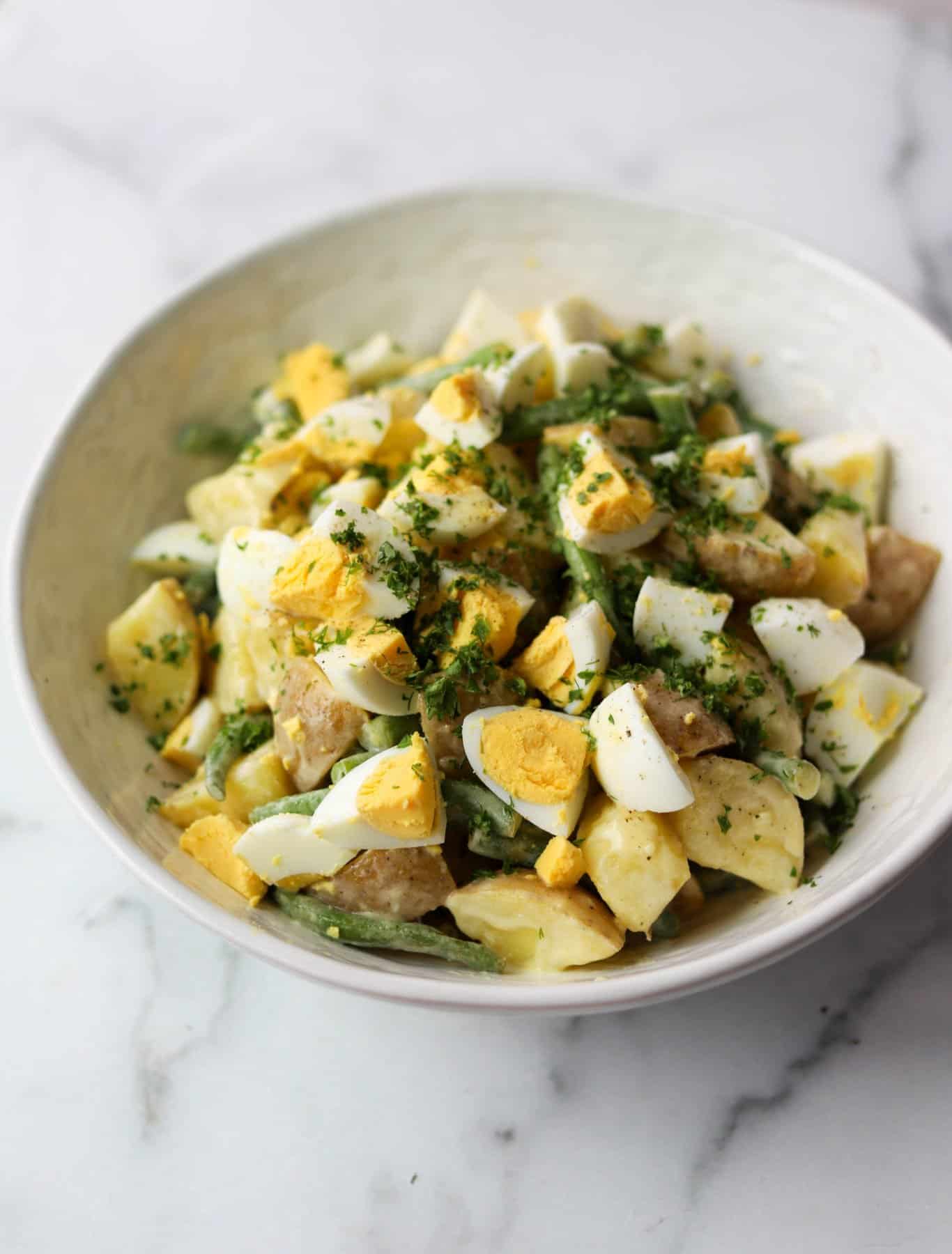 Green bean potato salad in a white bowl