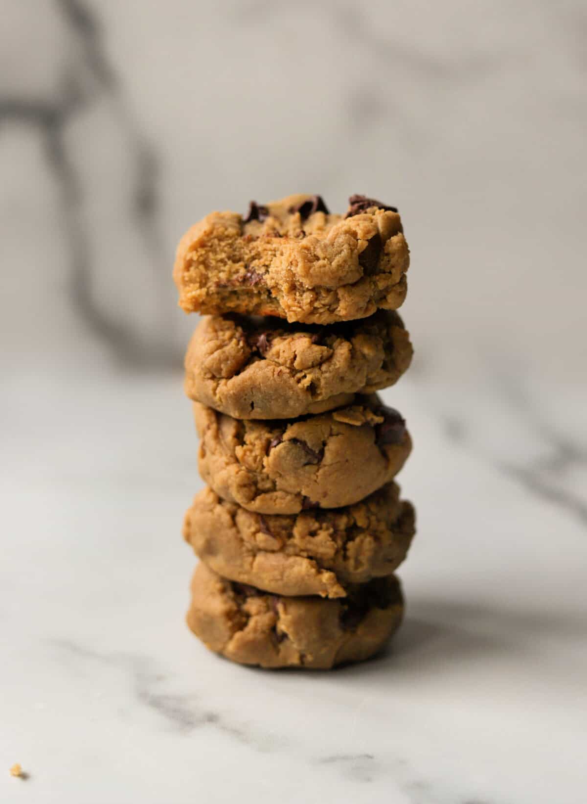 A front shot of a stack of peanut butter honey cookies with a bite taken out of one.