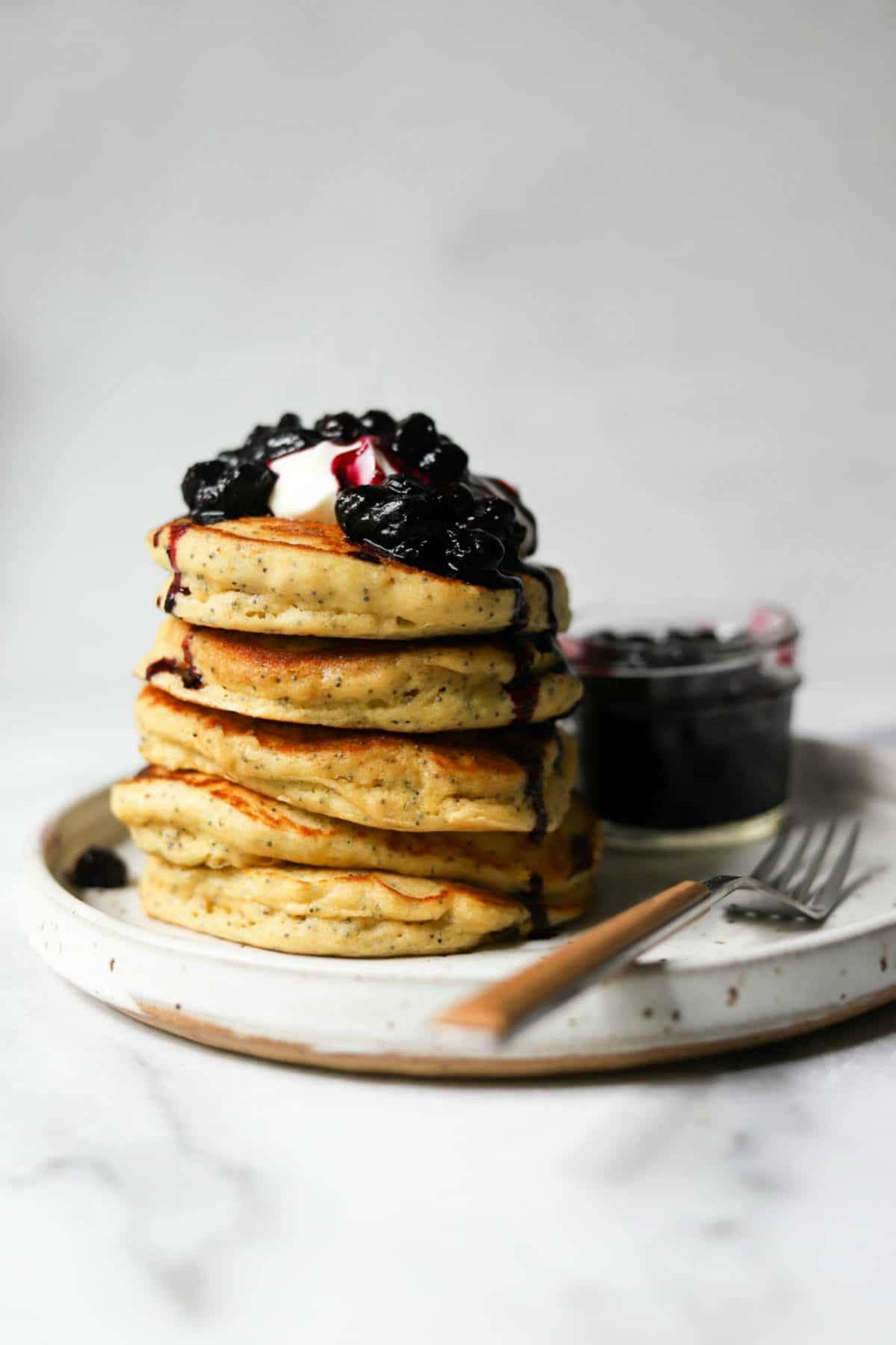 Stack of lemon ricotta pancakes on a white plate.