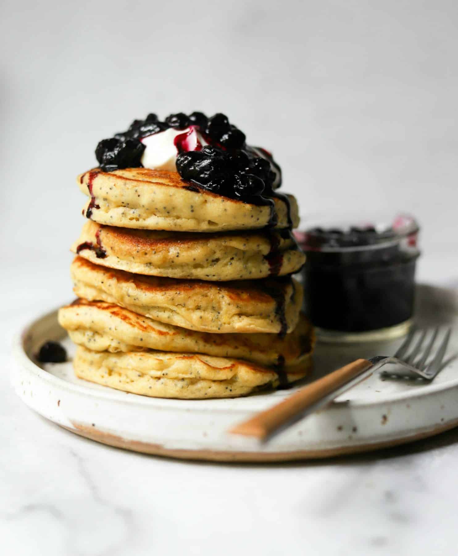 Stack of lemon ricotta pancakes on a white plate