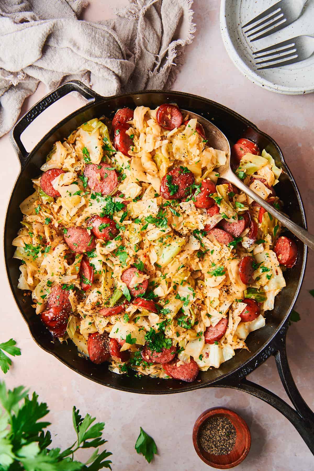 An overhead shot of a skillet filled with cabbage and sausage.