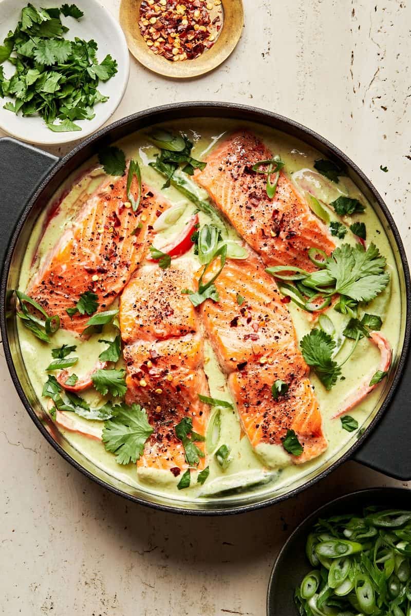 An overhead shot of a skillet of green salmon curry.