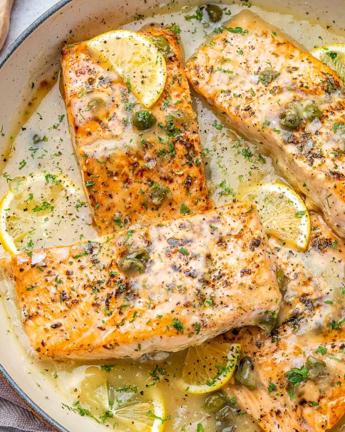 An overhead shot of a skillet of salmon piccata.