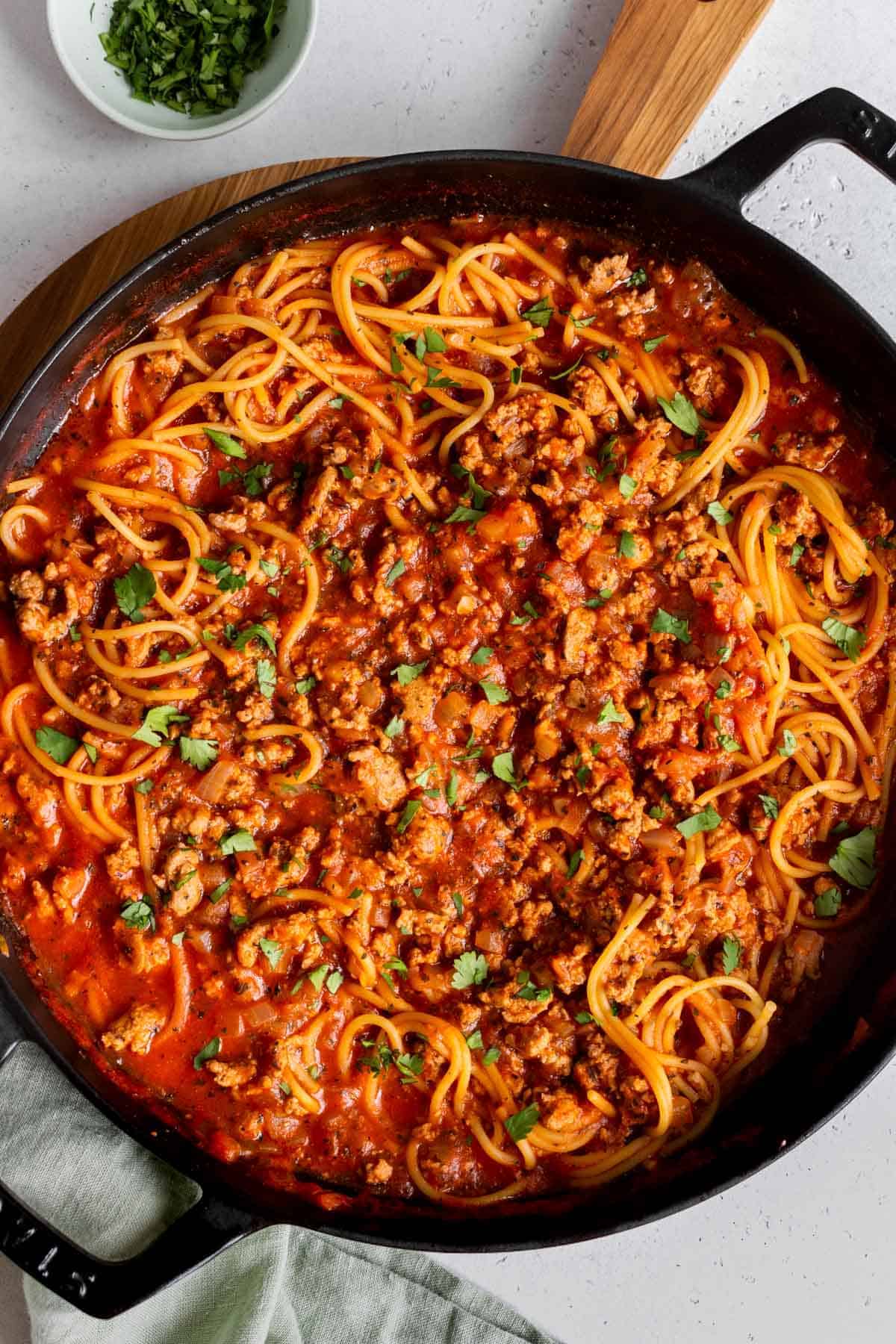 An overhead shot of a cast iron skillet filled with turkey spaghetti.