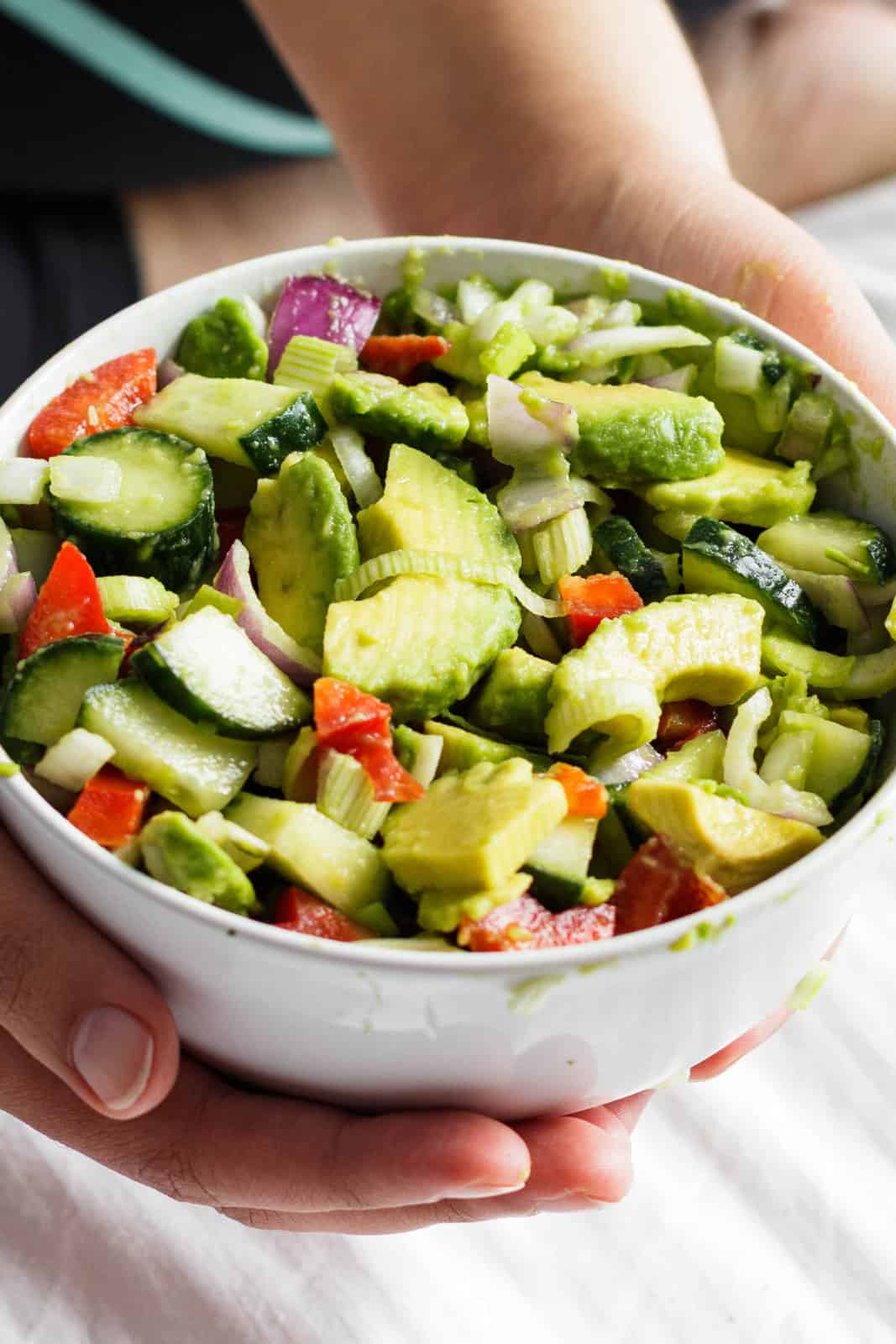 A front shot of a bowl of avocado, red onion and cucumber salad.