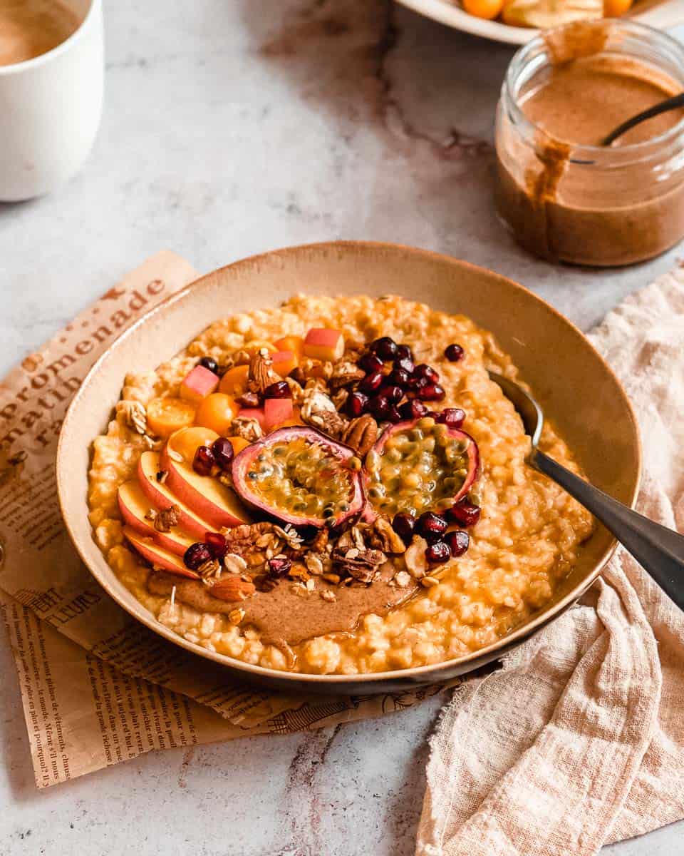 A front shot of a big bowl of pumpkin oatmeal with fruit and nuts on top.