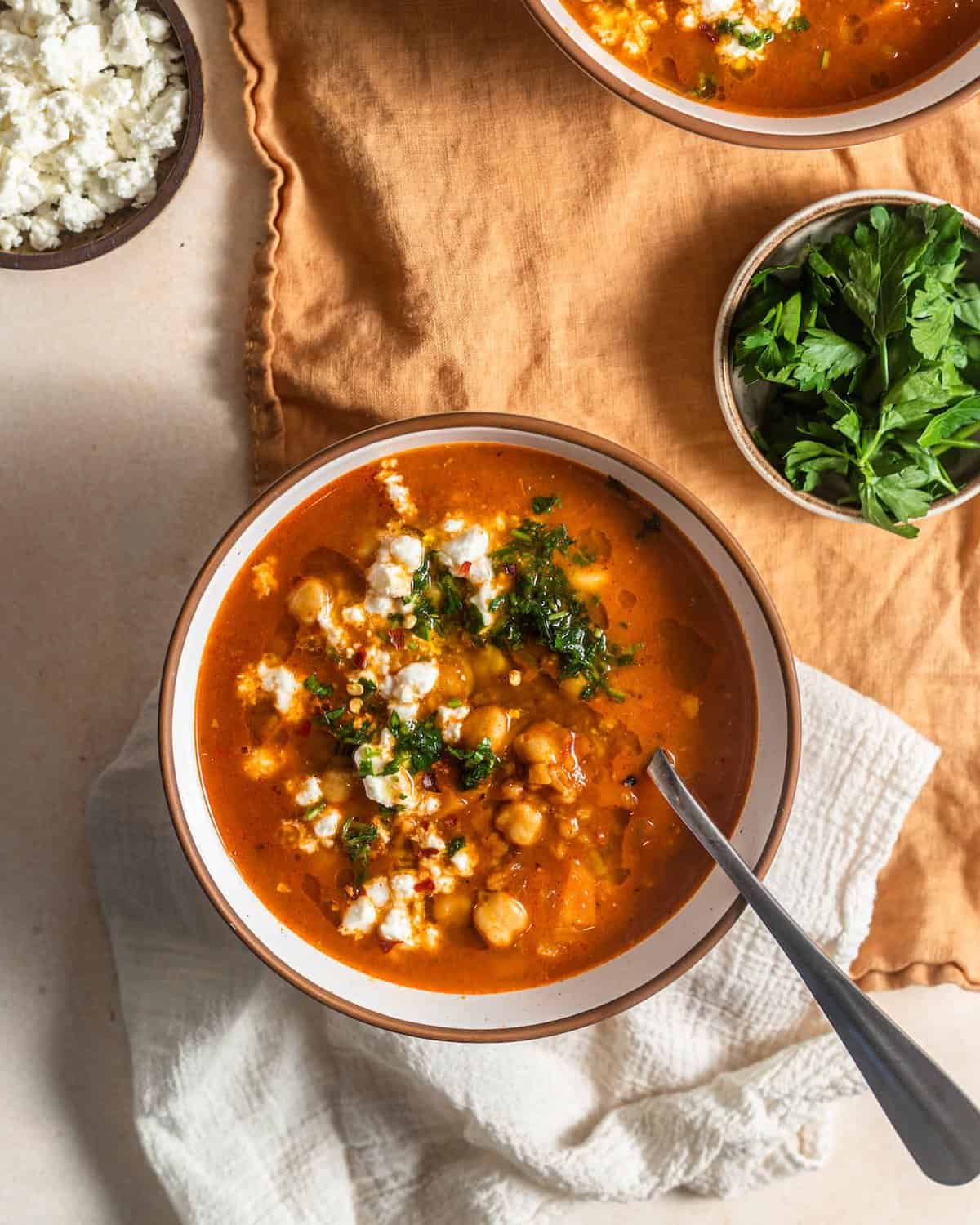 An overhead shot of a bowl of smoky farro soup with feta and herbs.