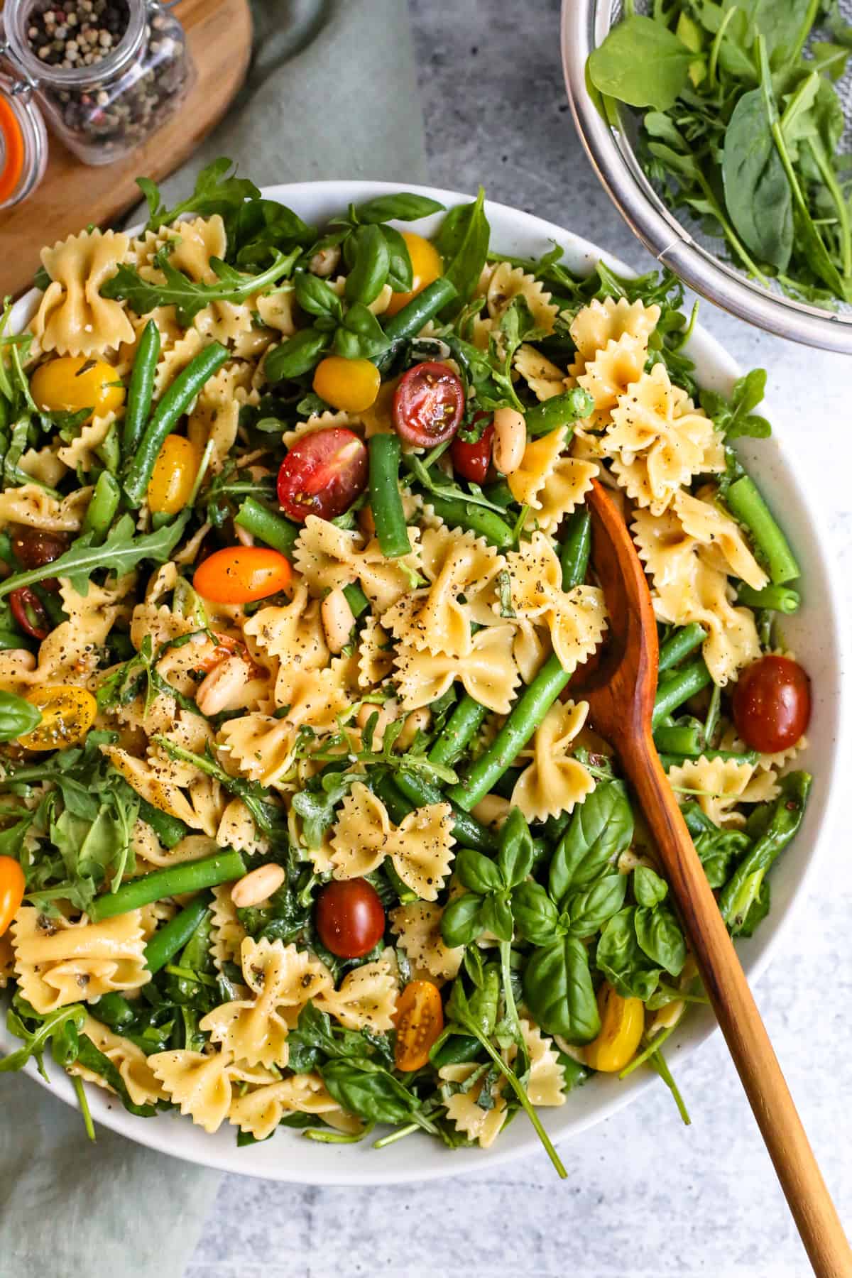 An overhead shot of a bowl of pasta salad with beans and leafy greens.