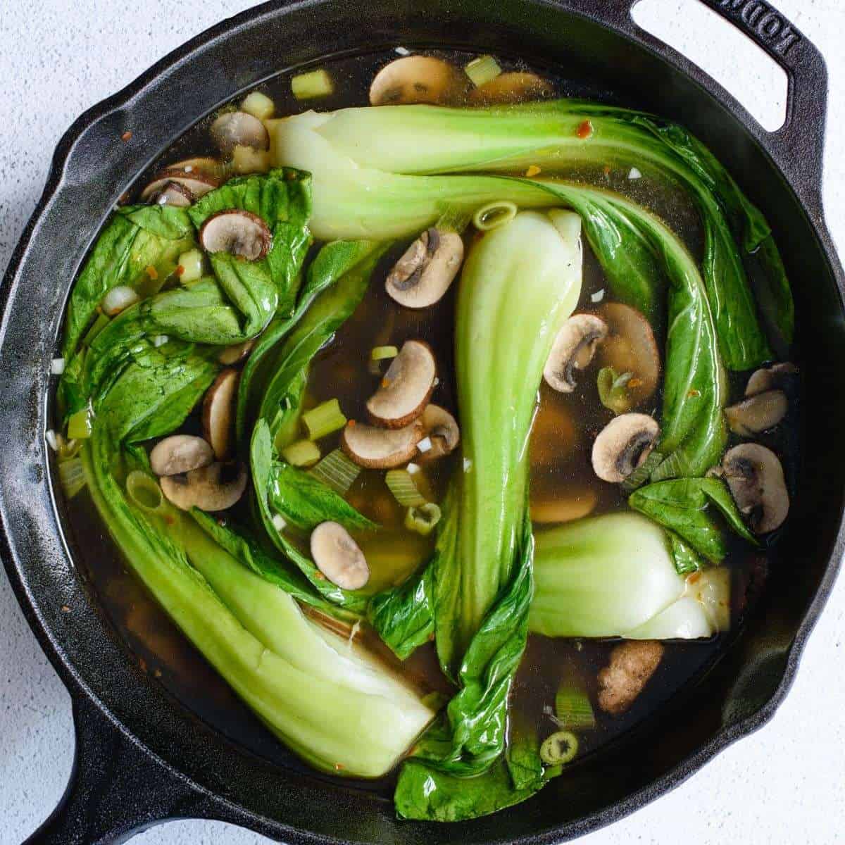 Bok choy mushroom soup in a cast iron skillet.