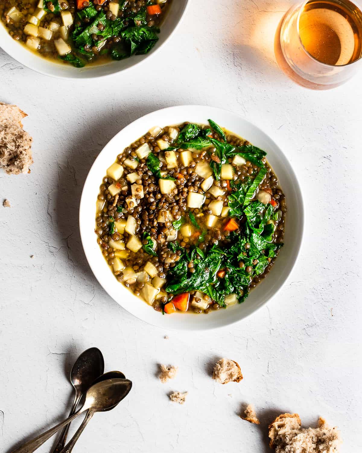 An overhead shot of a bowls of hearty lentil soup with greens.