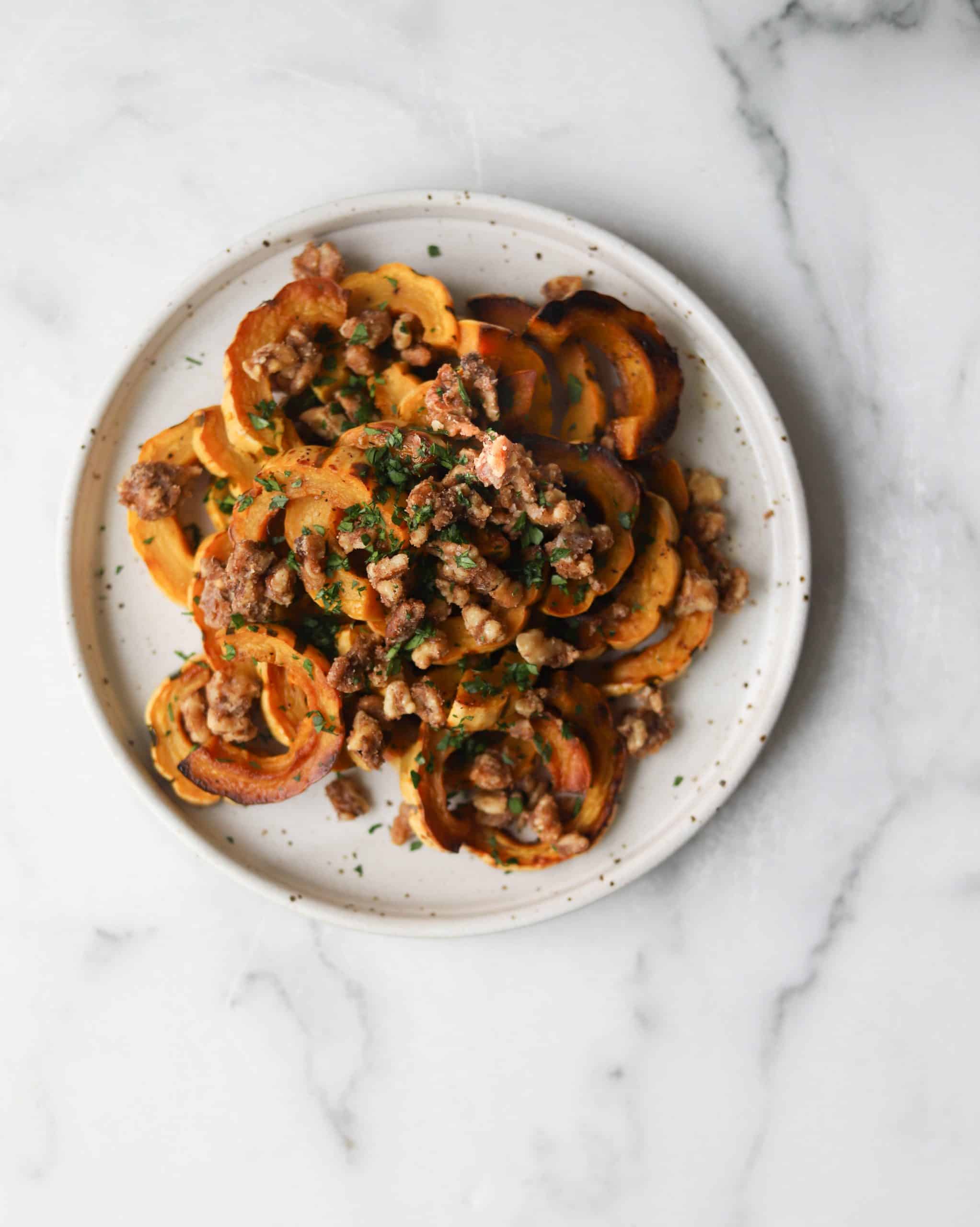 Delicata squash with walnut crumble on a white speckled plate