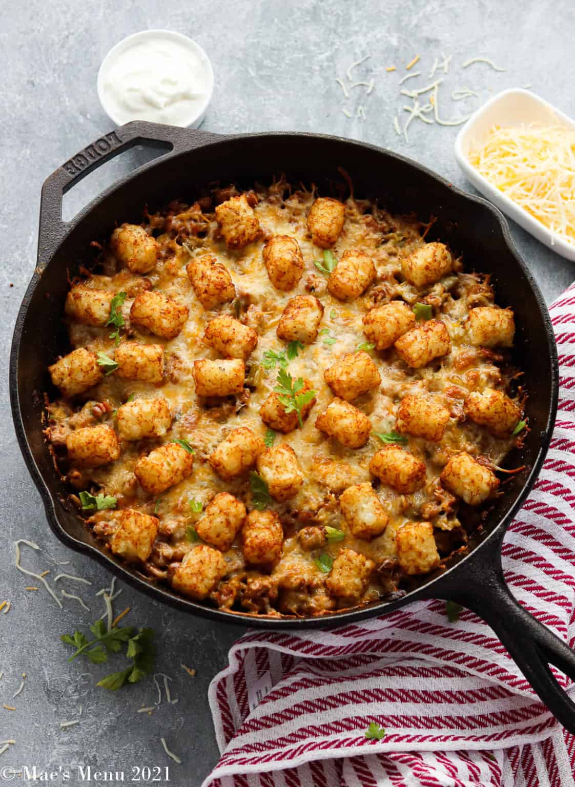 An overhead angled shot of a skillet filled with tater tot casserole.