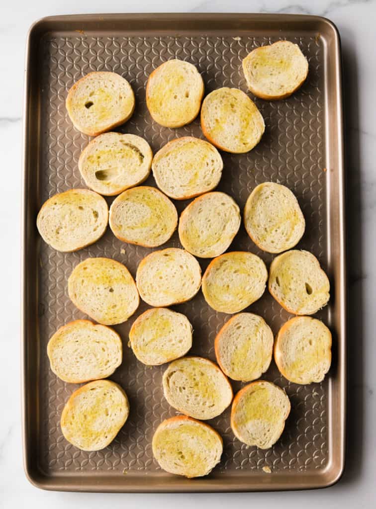 An overhead shot of a baking sheet with toasted crostinis.