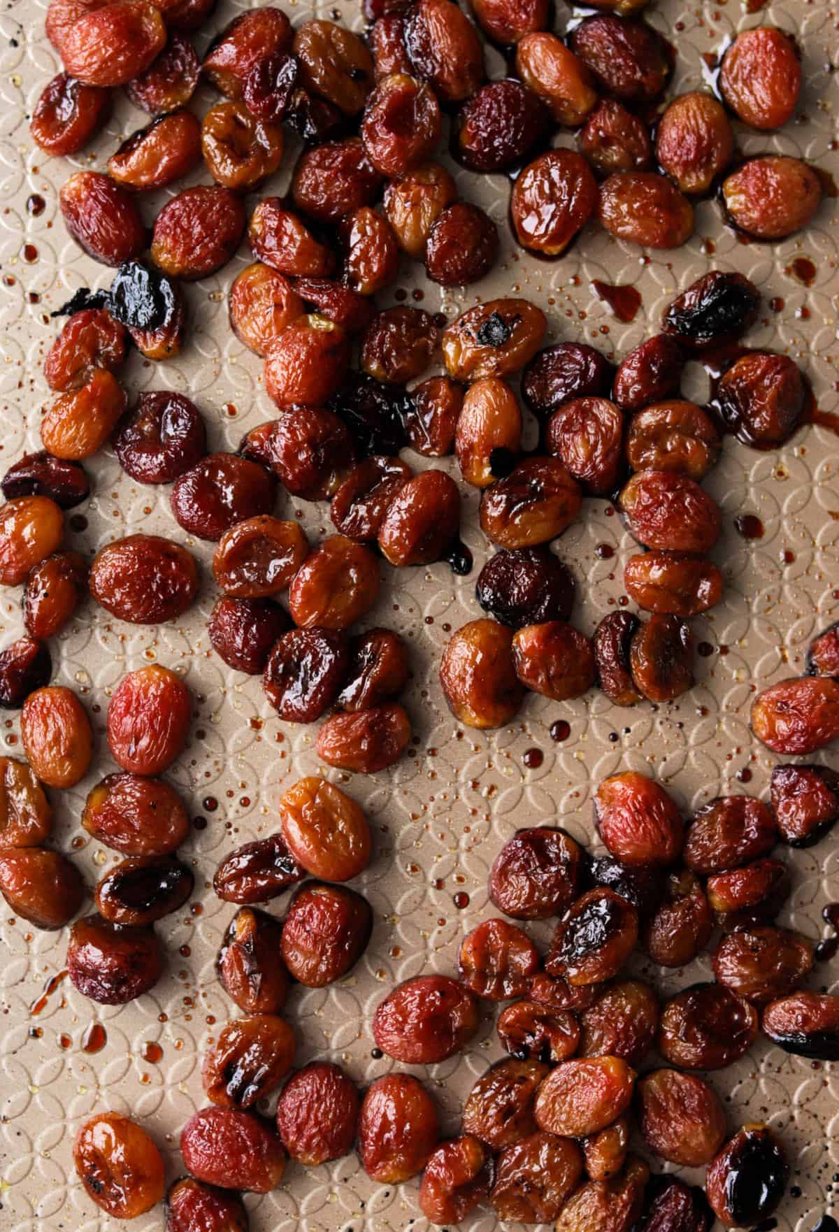 An overhead close up shot of balsamic roasted grapes on a sheet pan.