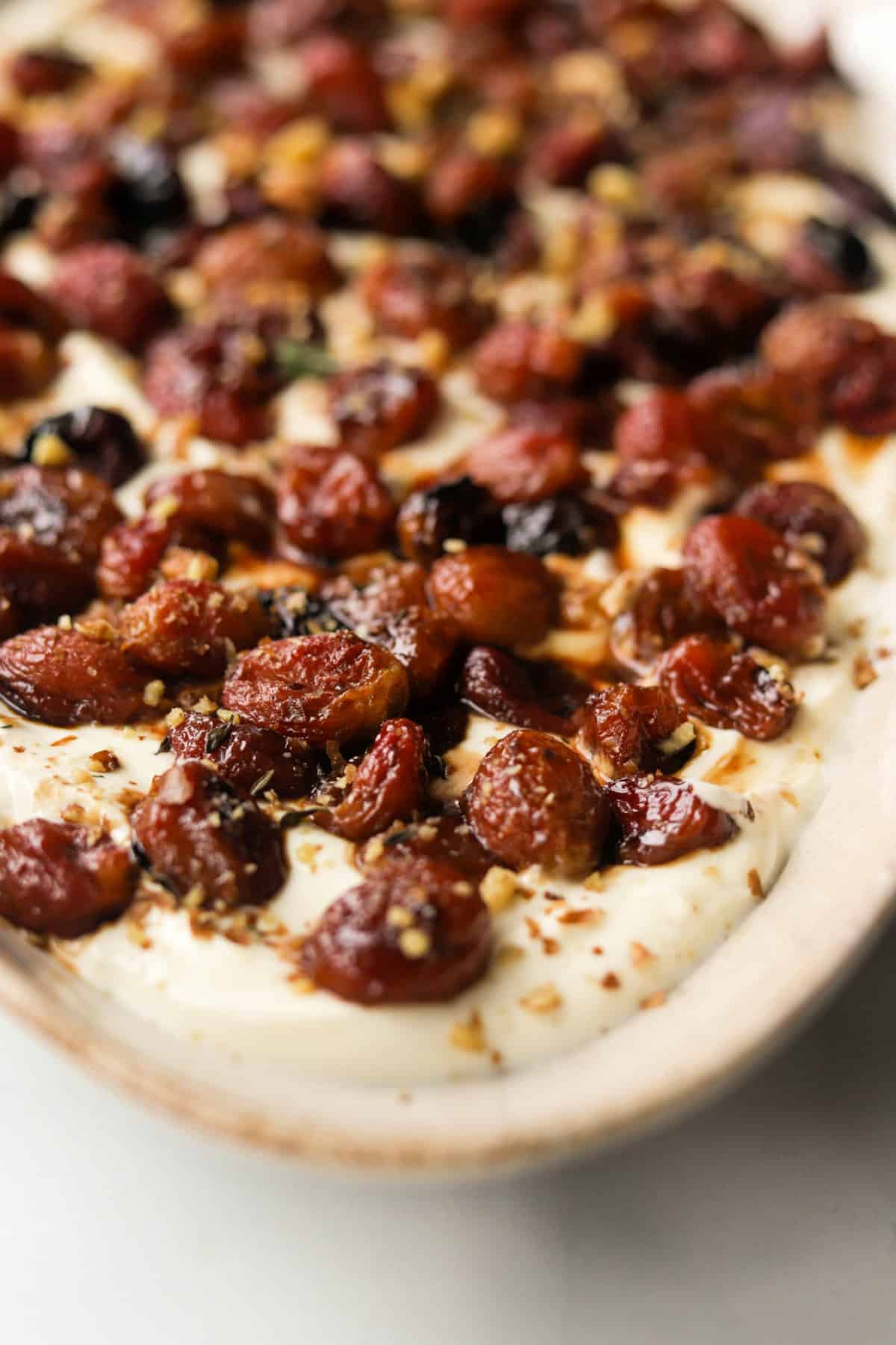 A close up front shot of roasted grapes on ricotta dip.