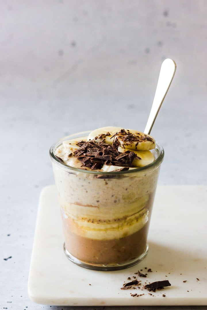 A side shot of a layered glass with chocolate banana overnight oats.