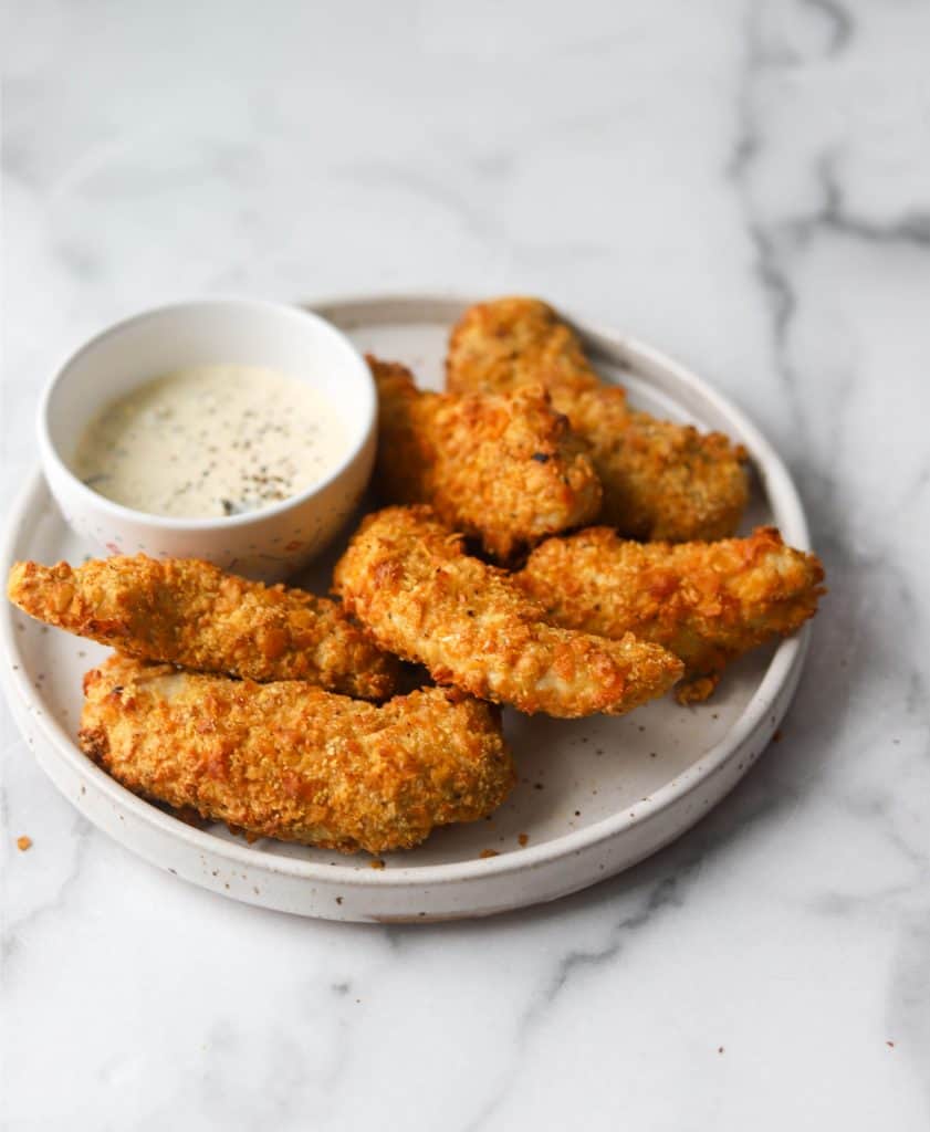 Side view of chicken tenders on a white plate