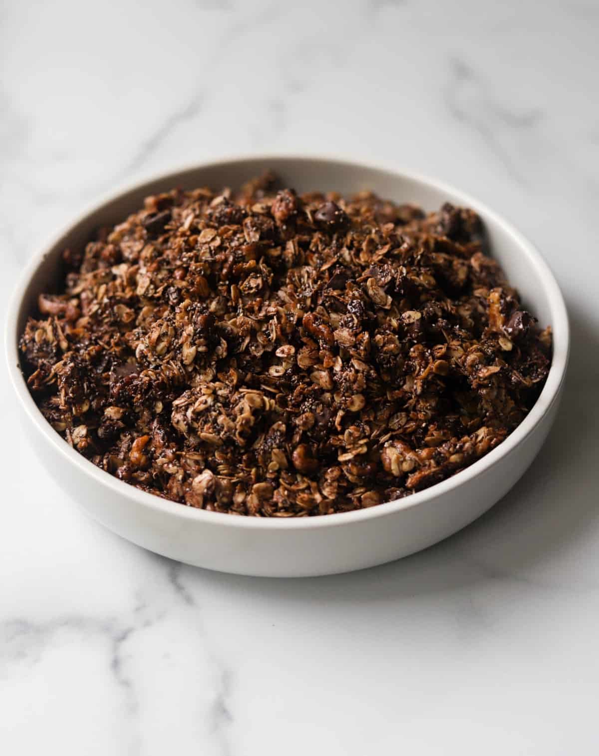 A side shot of a bowl of chocolate granola with coconut.