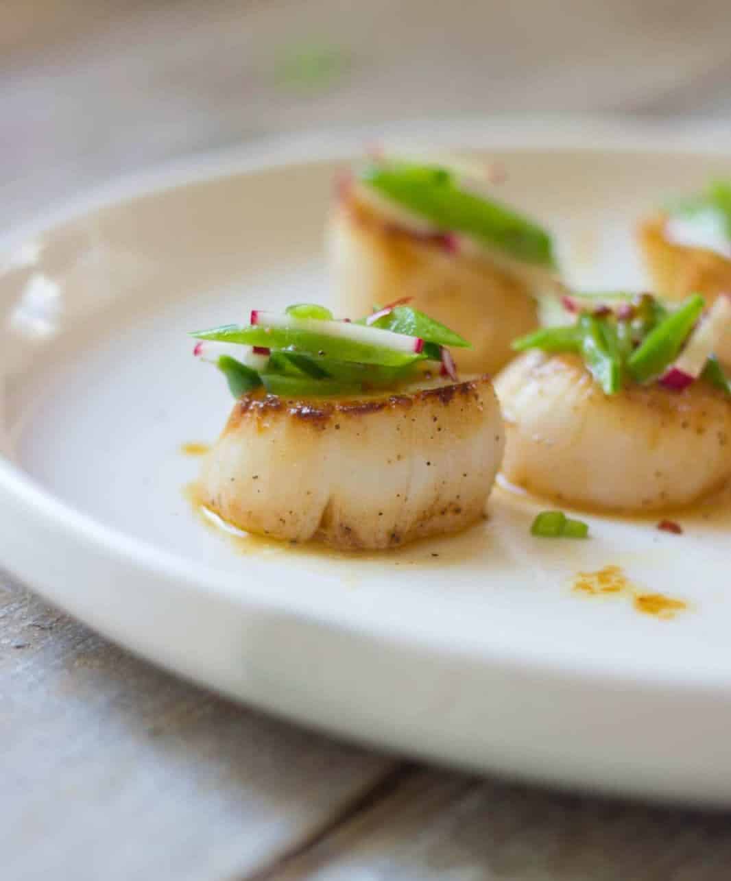 A side shot of a plate of scallops.