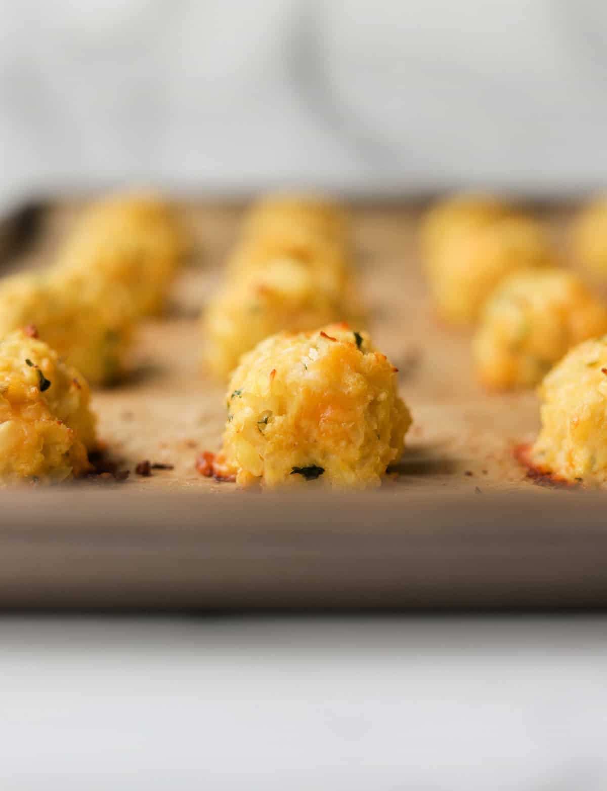 A front shot of cauliflower tater tots lined on a baking sheet.