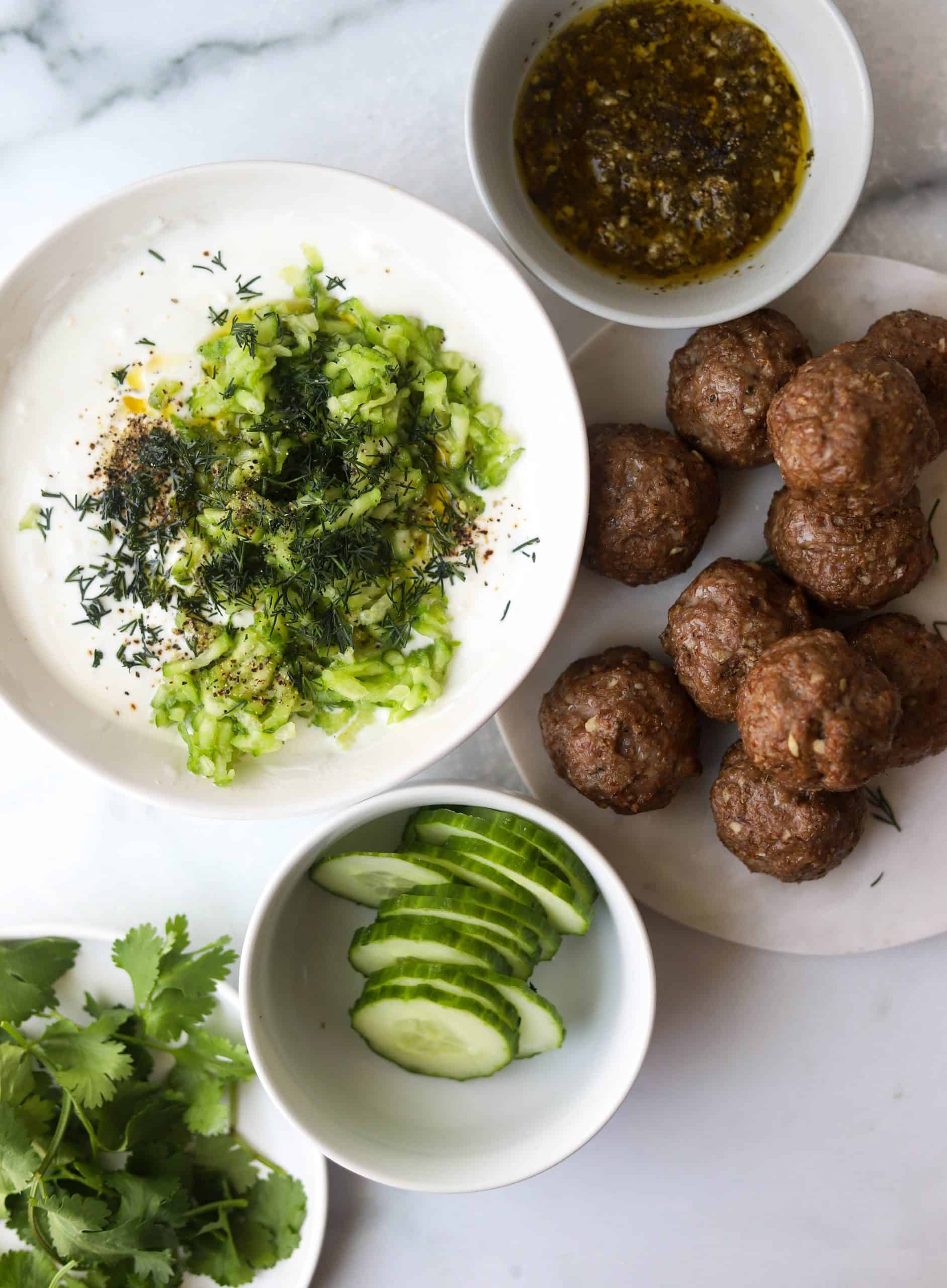 An overhead shot of bowls of meatballs and gyro ingredients.