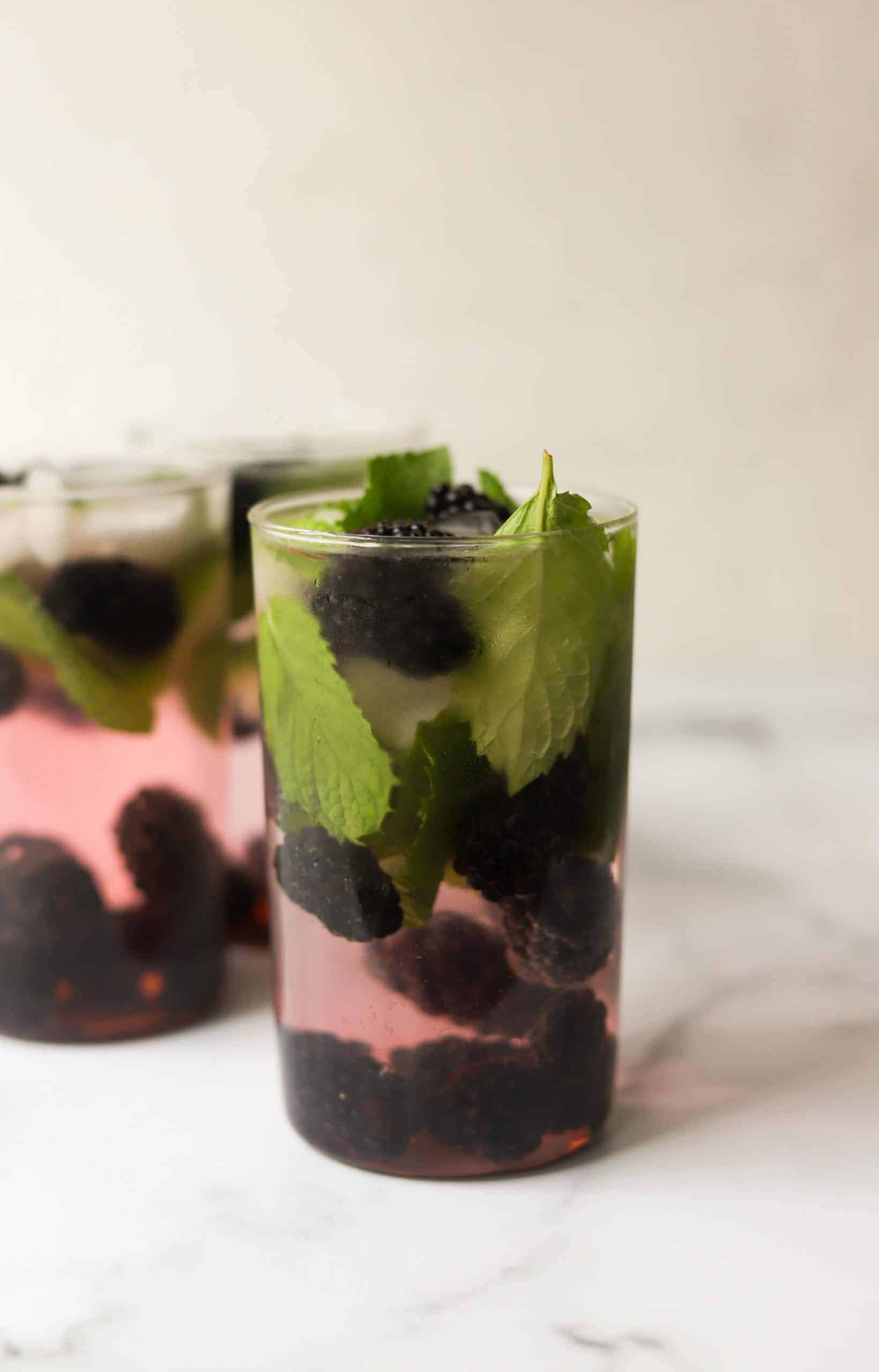 A front shot of blackberry mojitos in clear glasses.
