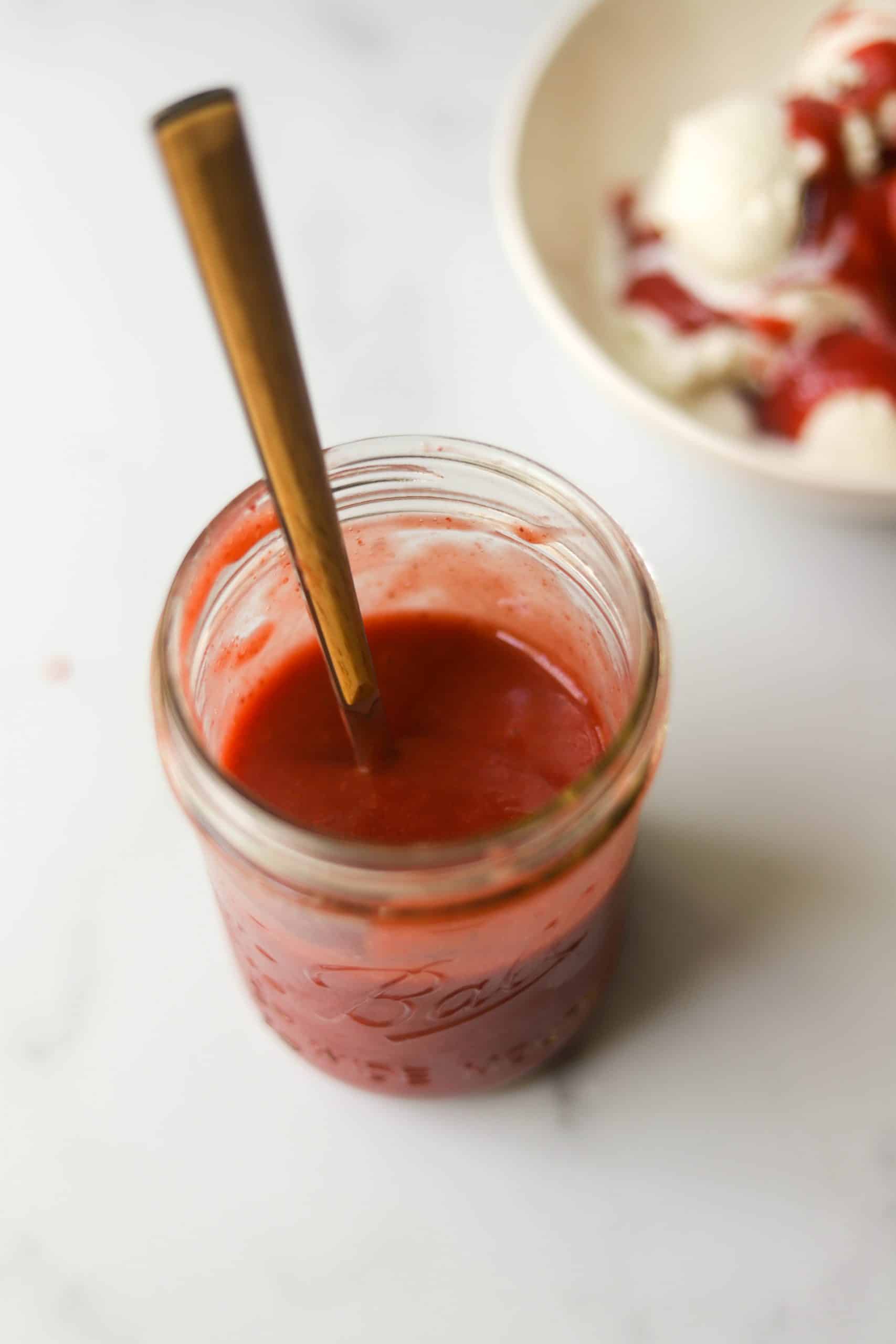 A clear jar filled with strawberry coulis.