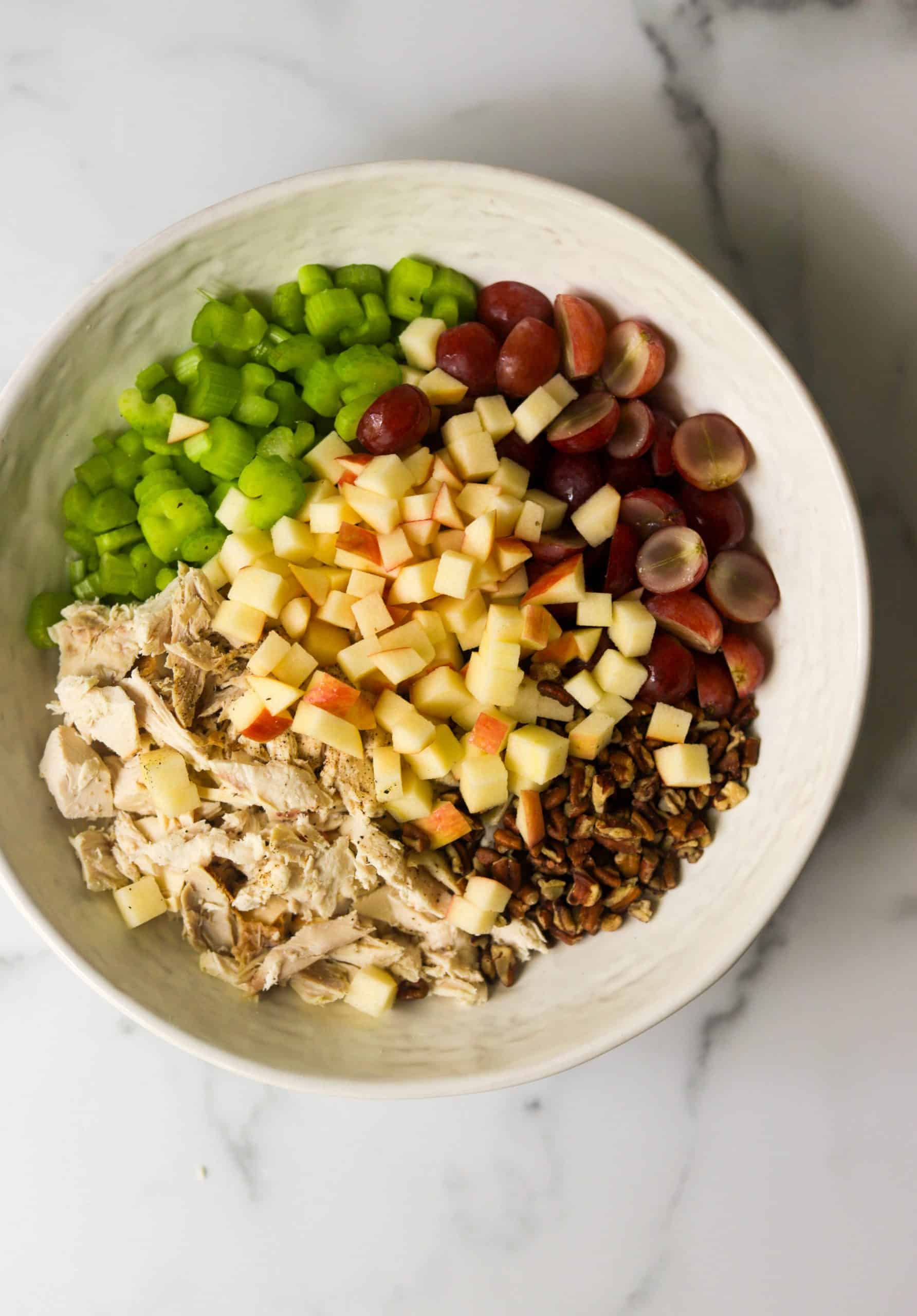 A big white bowl with waldorf chicken salad ingredients.