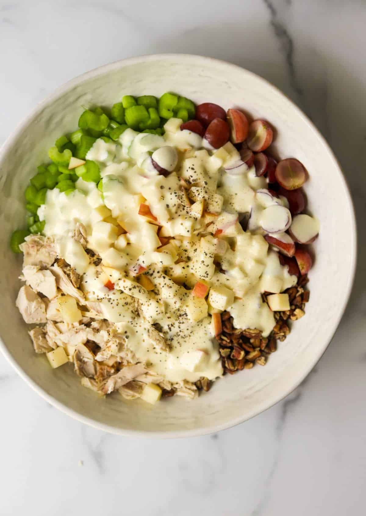 A big white bowl with chicken salad ingredients.