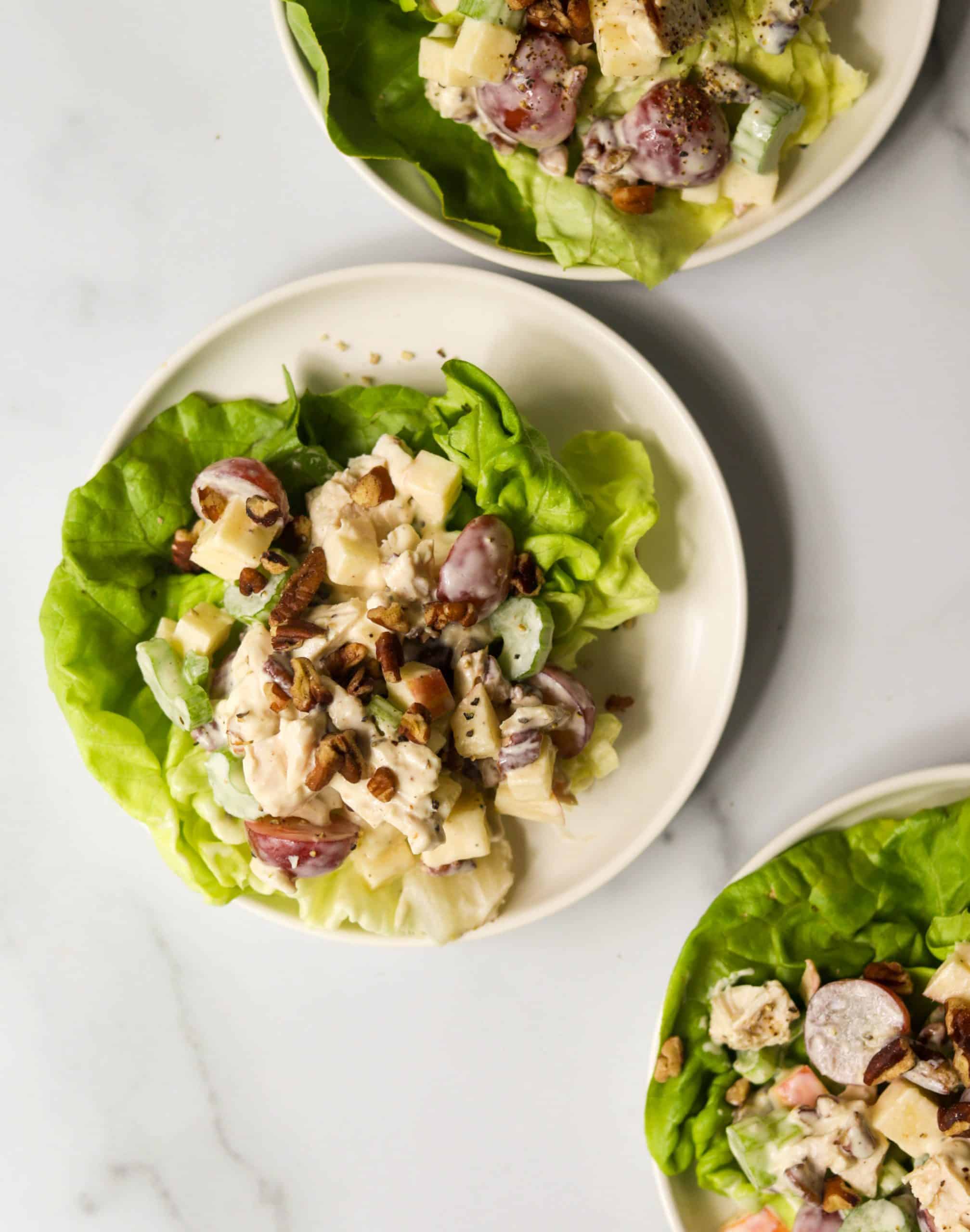 White plates with chicken salad on a marble backdrop.