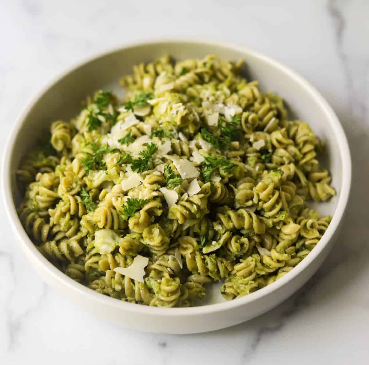 A side shot of a bowl of broccoli pesto pasta.