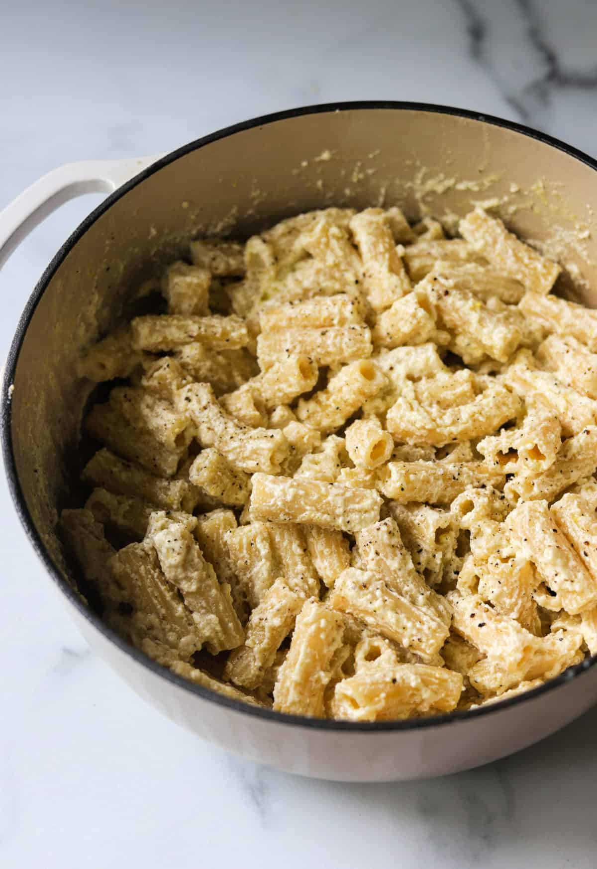 A front angled shot of a pot of lemon ricotta pasta with black pepper on top.