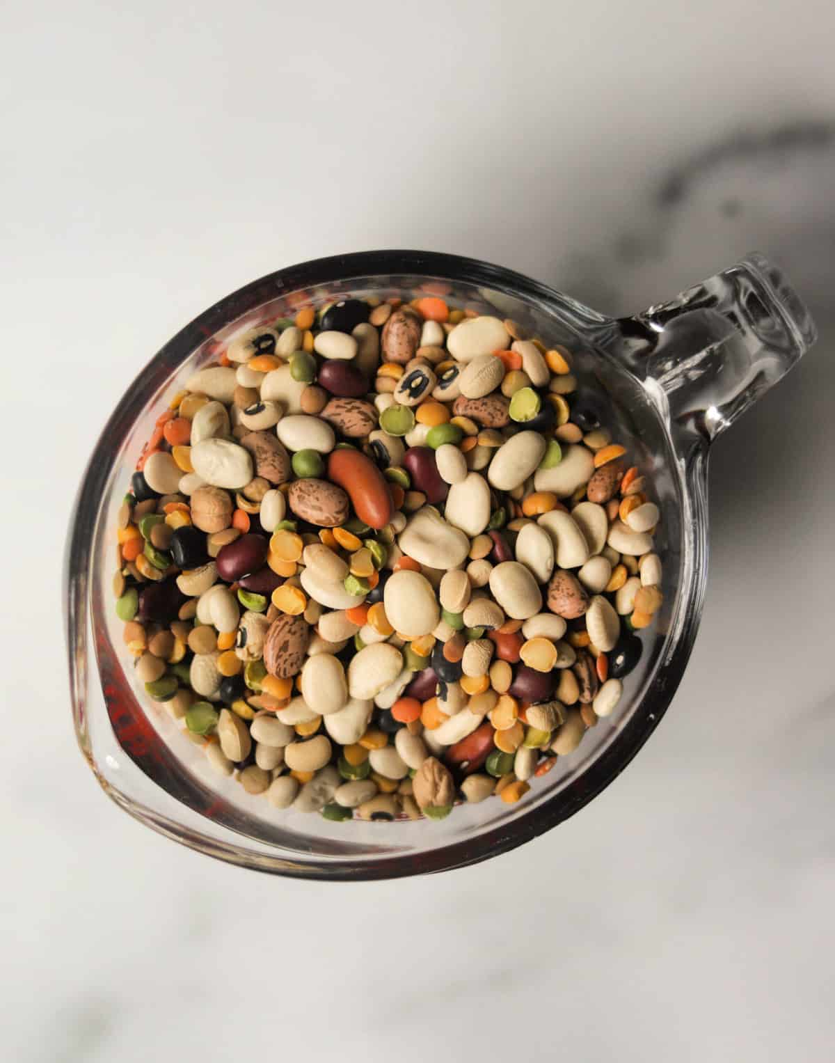 An overhead shot of a glass cup filled with dried beans.
