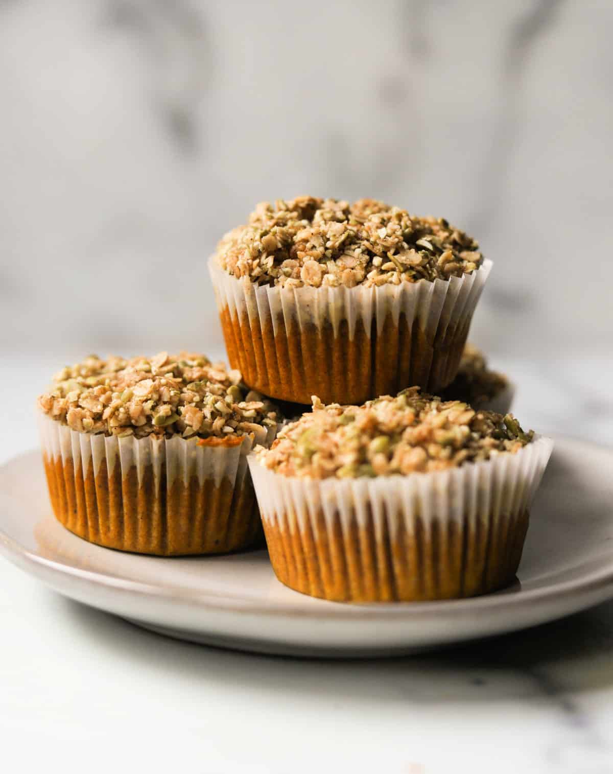 A front shot of pumpkin muffins with pistachio crumble stacked.