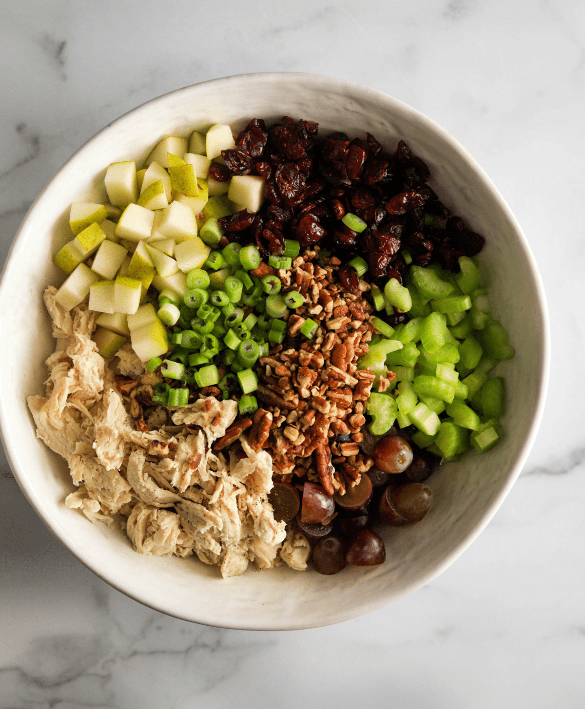 An overhead shot of a bowl of chicken salad ingredients.