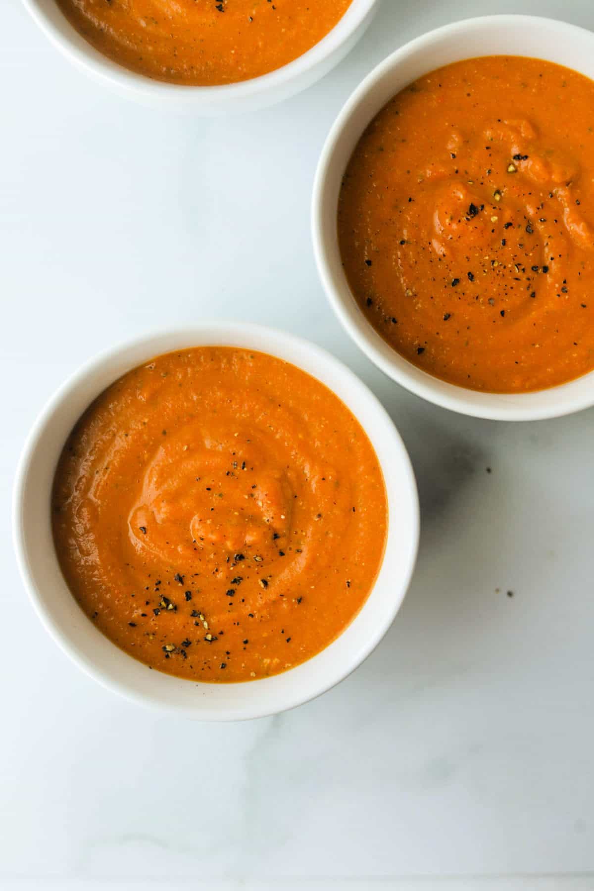 An overhead shot of bowls of spiced carrot soup.