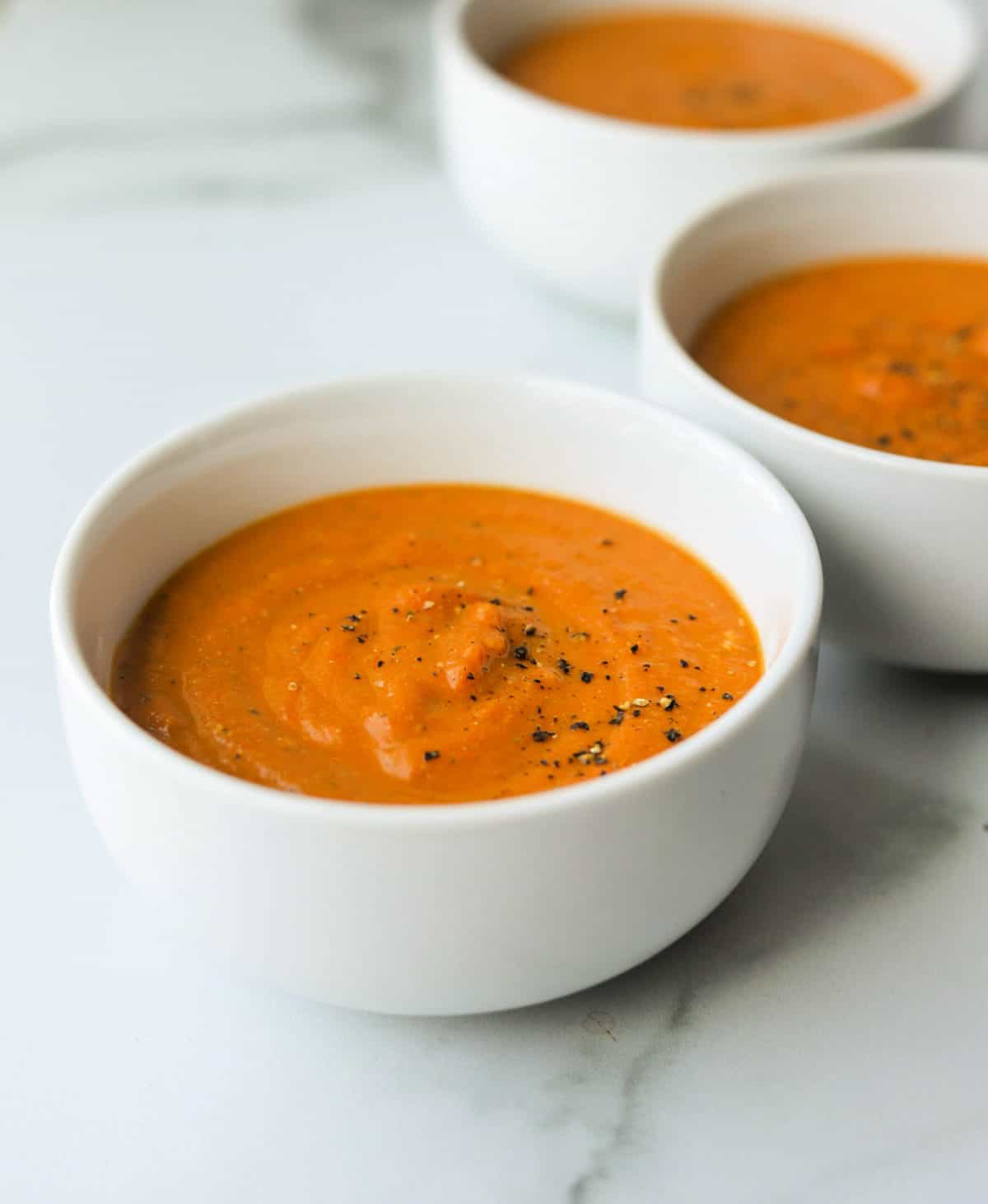 A side shot of bowls of spiced carrot soup.