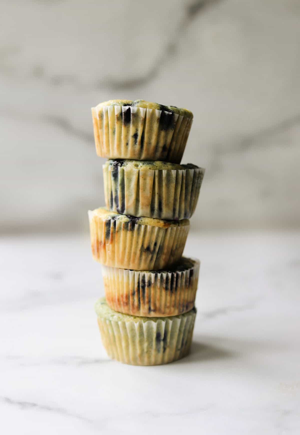 A front shot of a stack of 5 blueberry muffins.