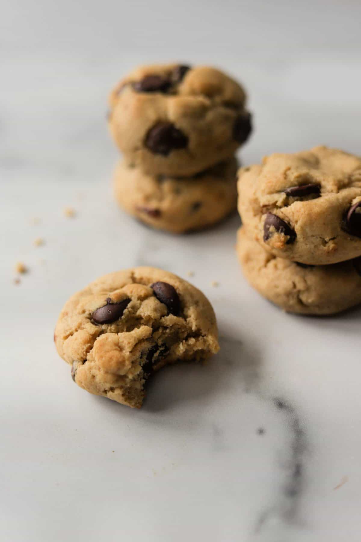 A side shot of stacked chocolate chip cookies and one off on its own.