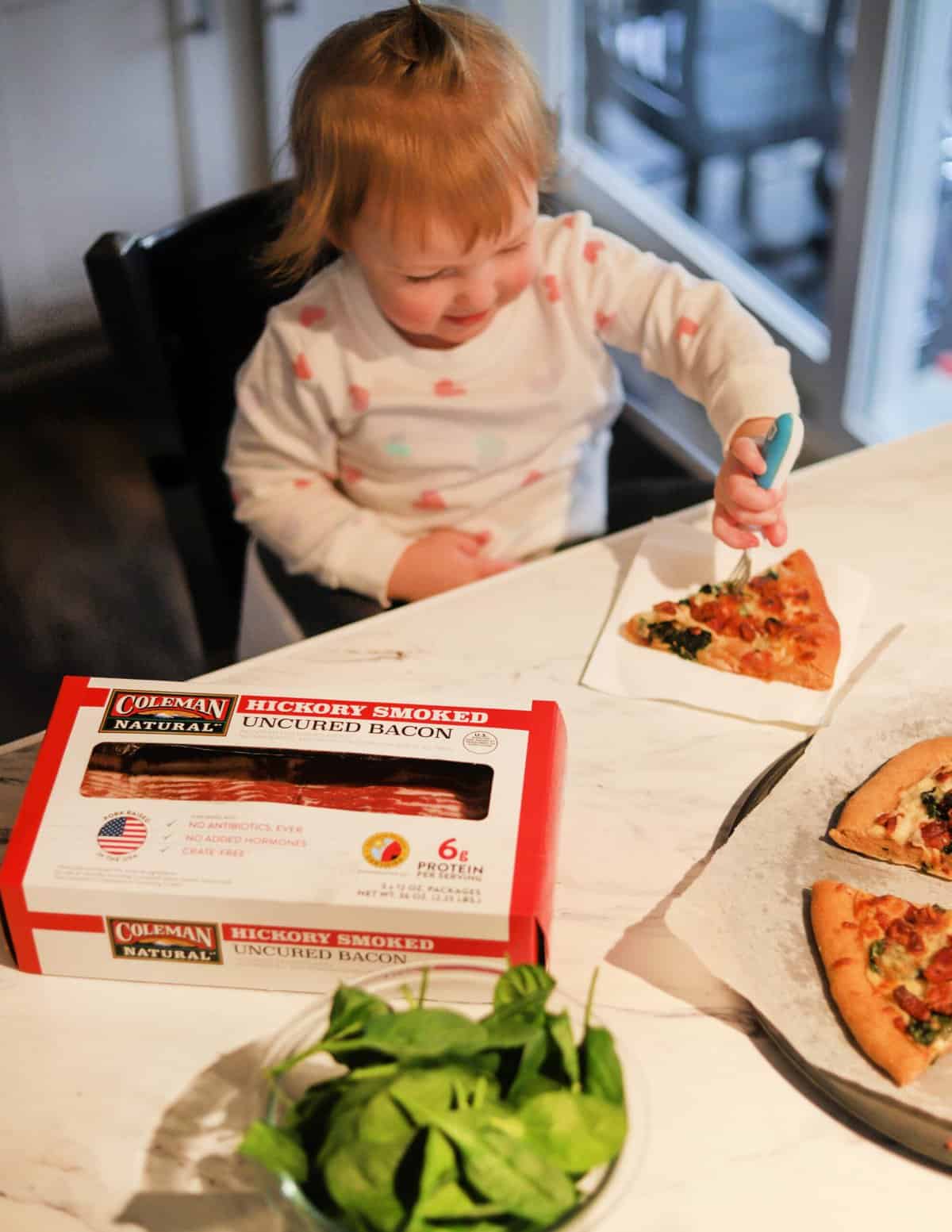 A side shot of a toddler eating pizza.